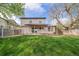 Spacious backyard with a well-kept lawn, mature trees, and a back patio seating area at 6398 S Emporia Cir, Englewood, CO 80111