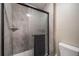 Shower with textured gray tile and glass door, plus shelf, and a view of the toilet at 6398 S Emporia Cir, Englewood, CO 80111