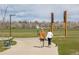 People walk a small dog on a paved path through a grassy park with metal park signage visible in the background at 5242 Columbine Ln, Denver, CO 80221