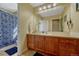 Well-lit bathroom featuring a wooden vanity and spacious shower with patterned curtain at 5338 Potentilla St, Brighton, CO 80601