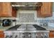 Stainless steel range and vent hood with tile backsplash at 5338 Potentilla St, Brighton, CO 80601