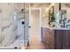 Stylish bathroom with a walk-in shower featuring glass door, a wooden double vanity and modern lighting at 1150 W Caley Ave, Littleton, CO 80120