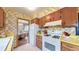 Vintage kitchen with white appliances, wood cabinets, and floral wallpaper at 2300 Joliet St, Aurora, CO 80010