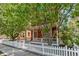 Charming home with a cozy front porch, white picket fence, and lush greenery at 2737 Ulster St, Denver, CO 80238