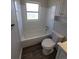 Bathroom featuring a white tiled shower-tub combination, window, vinyl floors, and white fixtures at 5552 Abilene St, Denver, CO 80239