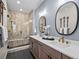 Modern bathroom with a dual sink vanity, decorative mirrors, walk-in shower, and neutral tile at 1787 W 166Th Ave, Broomfield, CO 80023