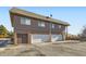 Exterior shot of building with multiple garages and dark brown siding with brick accents at 9943 Croke Dr, Denver, CO 80260