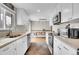 Bright kitchen with white cabinetry, stone countertops, and appliances with a view to the dining area at 8353 Adams Way, Denver, CO 80221