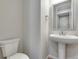 Bathroom with a pedestal sink, toilet, modern finishes, and a framed mirror at 6863 Oak Canyon Cir, Castle Pines, CO 80108