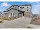 Modern two-story home featuring gray siding, stone accents, and a spacious driveway leading to an attached garage at 6863 Oak Canyon Cir, Castle Pines, CO 80108