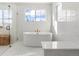 Luxurious bathroom featuring a soaking tub, white marble tile, glass enclosed shower, and modern fixtures at 15 Latigo Pl, Littleton, CO 80123