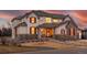 Inviting two-story home featuring stone accents, a covered porch, and warm interior lighting at 15 Latigo Pl, Littleton, CO 80123