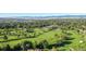 Expansive aerial view of lush golf course with mature trees, a lake, and mountain views at 15 Latigo Pl, Littleton, CO 80123