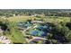 Aerial view of tennis courts and clubhouse with a pool amid lush green landscaping at 15 Latigo Pl, Littleton, CO 80123