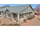 A green shingled home exterior with brick foundation, a small patio, and beige trim under a bright blue sky at 15123 Xenia St, Thornton, CO 80602
