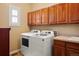 Well-organized laundry room with modern washer and dryer units, wooden cabinets, and tiled countertop at 11023 Glengate Cir, Highlands Ranch, CO 80130