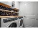 Bright laundry room features modern appliances, wooden shelving, and stylish wallpaper accent at 4604 Copeland Cir # 101, Highlands Ranch, CO 80126