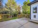 Large concrete patio with wooden railing surrounded by mature trees offering backyard privacy at 1020 S Ammons Cir, Lakewood, CO 80226