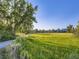 Large green space with tall grasses, scattered trees, and a building in the distance under a blue sky at 1020 S Ammons Cir, Lakewood, CO 80226