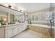 Bright bathroom with a double vanity, a soaking tub by the window, framed mirror, and light tile flooring at 11623 E Ida Ave, Englewood, CO 80111