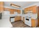 Functional kitchen with wood cabinets, white appliances, and wood-look vinyl flooring at 4678 S Lewiston Way, Aurora, CO 80015