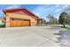 Oversized three-car garage with wooden doors, stone accents, and an expansive driveway at 5365 Eldridge St, Arvada, CO 80002