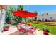 Inviting backyard patio with a red umbrella, outdoor seating, and lush green landscaping at 19730 E 58Th Pl, Aurora, CO 80019