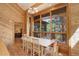Sunny dining room featuring wooden paneling, large windows and a table with seating for six at 13190 Coyote Song Trl, Conifer, CO 80433