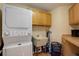 Efficient laundry area with stacked washer and dryer, utility sink, and wood cabinets at 13190 Coyote Song Trl, Conifer, CO 80433