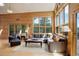 Open-concept living room featuring wood paneled walls, expansive windows, and comfortable sectional sofa at 13190 Coyote Song Trl, Conifer, CO 80433