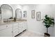Bright bathroom featuring double sinks, white cabinetry, updated mirrors, and neutral tile floor at 6874 S Detroit Cir, Centennial, CO 80122