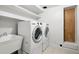 Laundry room with modern washer, dryer, utility sink, white shelving, and tiled floor at 6874 S Detroit Cir, Centennial, CO 80122