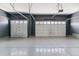 Spacious three car garage with epoxy flooring and two white overhead doors at 4992 Trails Edge Ln, Castle Rock, CO 80104