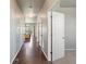 Long hallway with hardwood floors, white doors, and view into dining area with sliding glass doors at 1181 W 170 Th Ave, Broomfield, CO 80023