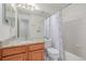 Bright bathroom featuring granite countertop on wood vanity and shower-tub combo with a white tile surround at 2905 S Deframe Way, Lakewood, CO 80228