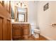 Well-lit powder room includes wood flooring, a wood vanity, framed mirror and a modern toilet at 1660 Old Antlers Way, Monument, CO 80132