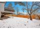 Snowy backyard, featuring a tall wooden fence and an open deck with access to the backyard at 16193 E Dickenson Pl, Aurora, CO 80013