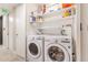 Functional laundry room with side-by-side washer and dryer and shelving for storage at 1201 N Williams St # 3B, Denver, CO 80218