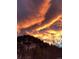 Dusk view shows colorful clouds over the home's treed hillside at 1037 Wagonwheel Gap Rd, Boulder, CO 80302