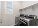 Laundry room featuring stainless steel washer and dryer, a window with natural light, and a shelf for storage at 27639 E 7Th Ln, Aurora, CO 80018