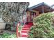 Charming backyard entrance featuring red stairs leading to a deck with striped awning and lush foliage at 1275 Niagara St, Denver, CO 80220