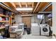 Unfinished basement area with washer and dryer hookups, storage shelves, and exposed pipes and beams at 1275 Niagara St, Denver, CO 80220