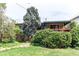 Well-maintained home exterior featuring a deck with green awning, lush landscaping, and a stone walkway at 1275 Niagara St, Denver, CO 80220
