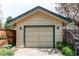 A detached garage with a gable roof, paneled door, side lights, and mature landscaping around the base at 1275 Niagara St, Denver, CO 80220