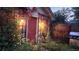A backyard outbuilding with a red door, climbing roses, white siding, and outdoor grill at 1275 Niagara St, Denver, CO 80220