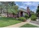 Inviting home featuring a brick exterior, charming front porch, and a well-maintained lawn with mature trees at 4231 S Fairplay Cir # A, Aurora, CO 80014