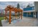 Backyard patio with pergola, seating, and modern concrete slab next to the two-story blue house at 1120 Hartford Dr, Boulder, CO 80305