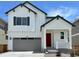 Charming two-story home with a red door, gray garage door, and a well-manicured lawn at 9286 Telluride Ct, Commerce City, CO 80022