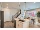 Bright kitchen with island, pendant lights, and stainless appliances leading to the dining area and staircase at 9769 E 62Nd Dr, Denver, CO 80238