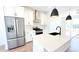 Kitchen boasts stainless steel appliances, a white island with a black sink and modern pendant lighting at 2668 W 68Th Ave, Denver, CO 80221